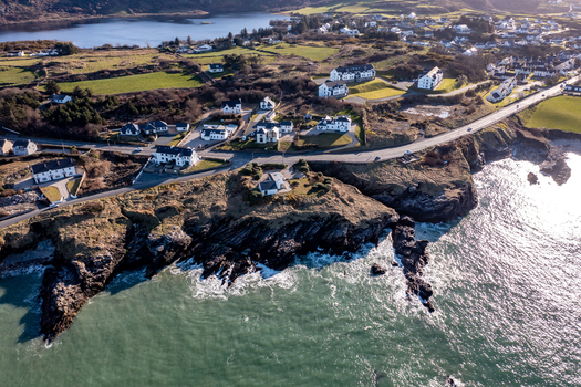Aerial view of Portnablagh village with white houses rocky cliffs and green fields along the rugged coastline of Portnablagh County Donegal Ireland. Aerial view of Portnablagh village with white houses rocky cliffs and green fields along the rugged coastline of Portnablagh County Donegal Ireland.