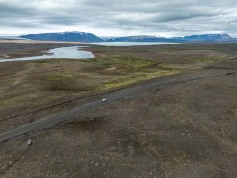 Aerial view of Kerlingarfjoll mountain range with a gravel road a winding river and volcanic terrain under a cloudy sky in Hrunamannahreppur Iceland. Aerial view of Kerlingarfjoll mountain range with a gravel road a winding river and volcanic terrain under a cloudy sky in Hrunamannahreppur Iceland.