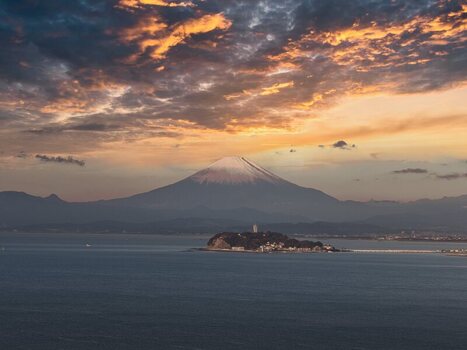 Aerial view of Mount Fuji and Enoshima Island at sunset with a snow capped peak and golden clouds over the ocean in Japan. Aerial view of Mount Fuji and Enoshima Island at sunset with a snow capped peak and golden clouds over the ocean in Japan.