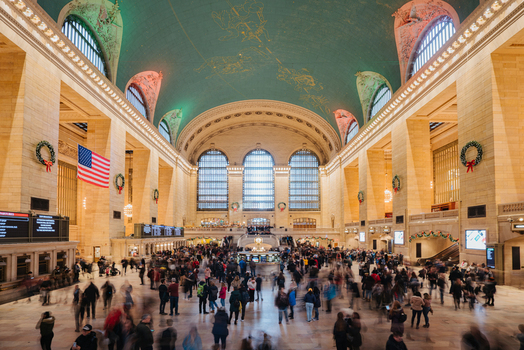 View of the bustling main concourse of Grand Central Terminal with its iconic celestial ceiling mural arched windows and holiday decorations in New York New York United States.