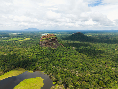 Aerial view of Sigiriya Lion Rock rising above the lush green jungle and a calm lake under a cloudy sky Sigiriya Central Province Sri Lanka. Aerial view of Sigiriya Lion Rock rising above the lush green jungle and a calm lake under a cloudy sky Sigiriya Central Province Sri Lanka.