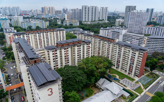 Aerial view of HDB public housing blocks with solar panels on rooftops lush green trees and urban infrastructure in Singapore Singapore. Aerial view of HDB public housing blocks with solar panels on rooftops lush green trees and urban infrastructure in Singapore Singapore.