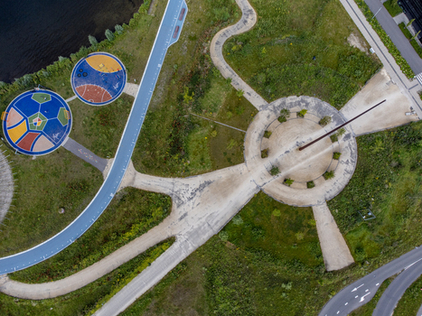 Aerial view of a sundial and colorful circular designs amidst green fields and concrete paths Utopia Flevoland Netherlands.