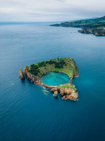 Aerial view of Vila Franca do Campo Islet a volcanic crater island embracing a serene turquoise lagoon contrasted against the vast deep blue Atlantic Ocean Vila Franca do Campo Portugal.
