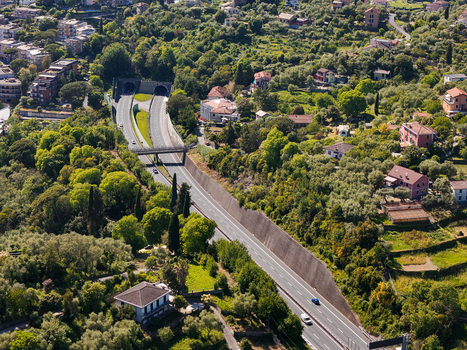 Aerial view of the A12 highway entering tunnels surrounded by residential houses and lush green vegetation in Genova Liguria Italy. Aerial view of the A12 highway entering tunnels surrounded by residential houses and lush green vegetation in Genova Liguria Italy.