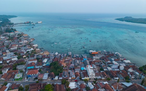 Aerial view of the coastal village of Karimunjawa with its dense rooftops harbor filled with small boats and turquoise bay waters in Karimunjawa Central Java Indonesia. Aerial view of the coastal village of Karimunjawa with its dense rooftops harbor filled with small boats and turquoise bay waters in Karimunjawa Central Java Indonesia.