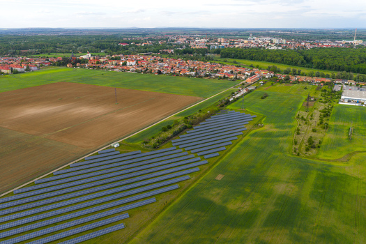 Aerial view of a solar farm with rows of photovoltaic panels in a green field near agricultural land and the town of Breclav South Moravian Region Czechia.