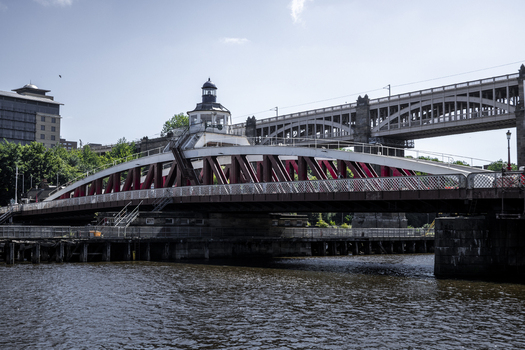 View of the historic Swing Bridge with its distinctive red steel arches and the High Level Bridge spanning the River Tyne in Newcastle upon Tyne England United Kingdom. View of the historic Swing Bridge with its distinctive red steel arches and the High Level Bridge spanning the River Tyne in Newcastle upon Tyne England United Kingdom.