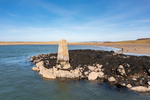 Aerial view of the stone trig point marker on a rocky outcrop covered in seaweed at Ballyness Bay in Ballyness County Donegal Ireland. Aerial view of the stone trig point marker on a rocky outcrop covered in seaweed at Ballyness Bay in Ballyness County Donegal Ireland.