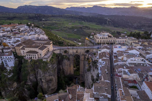 Aerial view of the iconic Puente Nuevo bridge spanning the deep El Tajo gorge with historic white buildings and terracotta rooftops of the old town in Ronda Andalusia Spain. Aerial view of the iconic Puente Nuevo bridge spanning the deep El Tajo gorge with historic white buildings and terracotta rooftops of the old town in Ronda Andalusia Spain.
