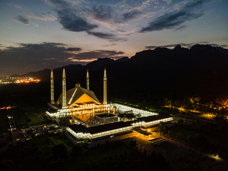 Aerial view of the illuminated Faisal Mosque with its iconic four minarets against the dark silhouette of the Margalla Hills at twilight in Islamabad Islamabad Capital Ter Pakistan. Aerial view of the illuminated Faisal Mosque with its iconic four minarets against the dark silhouette of the Margalla Hills at twilight in Islamabad Islamabad Capital Ter Pakistan.
