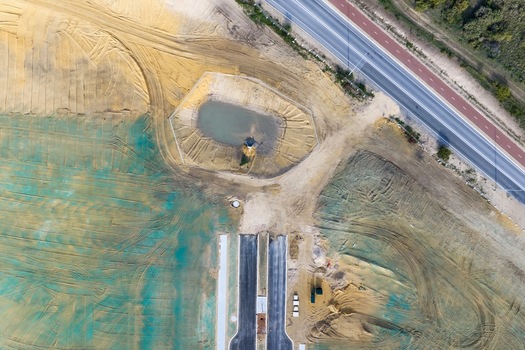 Aerial view of a residential development construction site with earthworks a drainage pond and new road infrastructure in Perth Western Australia Australia. Aerial view of a residential development construction site with earthworks a drainage pond and new road infrastructure in Perth Western Australia Australia.