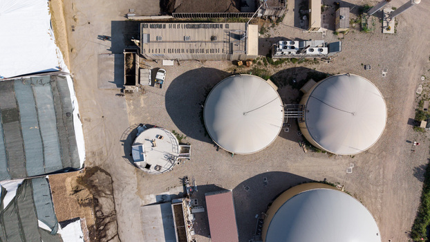 Aerial view of an agro farm biogas plant with large circular digester tanks industrial infrastructure and storage areas in Milan Lombardy Italy. Aerial view of an agro farm biogas plant with large circular digester tanks industrial infrastructure and storage areas in Milan Lombardy Italy.