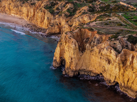 Aerial view of Ponta da Piedade with golden limestone cliffs turquoise Atlantic waters and rugged coastal rock formations in Lagos Faro Portugal.