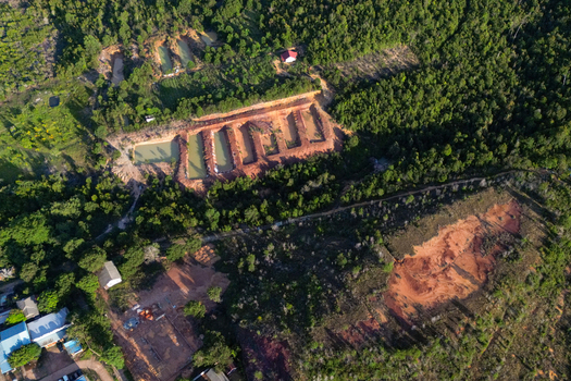 Aerial view of the Galang Baru area featuring red soil excavation sites surrounded by dense tropical greenery and rural buildings Galang Riau Islands Indonesia. Aerial view of the Galang Baru area featuring red soil excavation sites surrounded by dense tropical greenery and rural buildings Galang Riau Islands Indonesia.