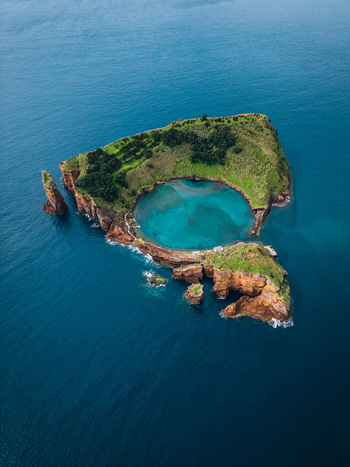 Aerial view of a vibrant islet with a turquoise lagoon encircled by verdant cliffs and rugged rock formations Vila Franca do Campo Azores Portugal.