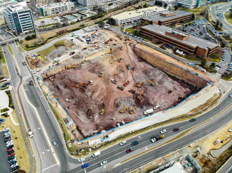 Reston Virginia United States 12 March 2019 Aerial view of a large construction site with heavy machinery excavators and earthmoving equipment near office buildings. Reston Virginia United States 12 March 2019 Aerial view of a large construction site with heavy machinery excavators and earthmoving equipment near office buildings.