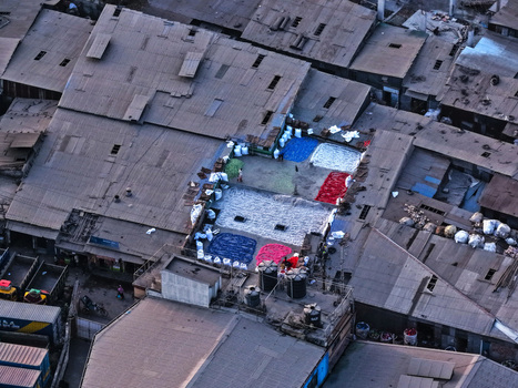 Aerial view of colorful textile materials spread out on a rooftop for processing surrounded by dense urban buildings in Dhaka Dhaka Division Bangladesh. Aerial view of colorful textile materials spread out on a rooftop for processing surrounded by dense urban buildings in Dhaka Dhaka Division Bangladesh.