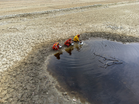 Gabura Union Bangladesh 25 April 2025 Aerial view of three women in colorful saris collecting water from a small pond amidst a parched and cracked dry landscape. Gabura Union Bangladesh 25 April 2025 Aerial view of three women in colorful saris collecting water from a small pond amidst a parched and cracked dry landscape.