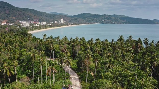 Aerial view of the coastline in Phuket featuring lush palm trees a winding road and the turquoise waters of the Andaman Sea Phuket Phuket Thailand. Aerial view of the coastline in Phuket featuring lush palm trees a winding road and the turquoise waters of the Andaman Sea Phuket Phuket Thailand.