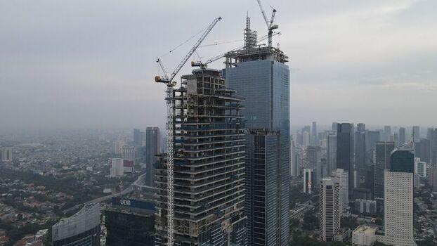 Kecamatan Menteng Daerah Khusus Ibukota Indonesia 03 December 2021 Aerial view of a skyscraper under construction with tower cranes and steel framework rising above the city skyline. Kecamatan Menteng Daerah Khusus Ibukota Indonesia 03 December 2021 Aerial view of a skyscraper under construction with tower cranes and steel framework rising above the city skyline.