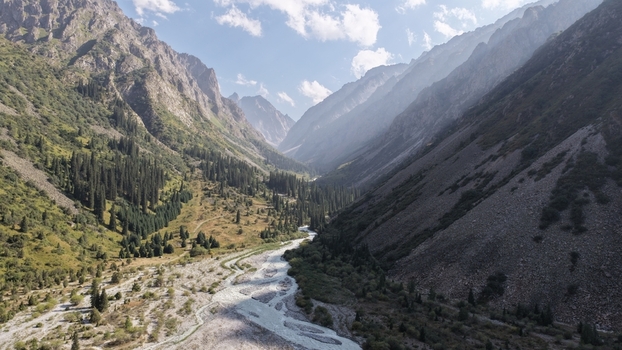 Aerial view of Ala Archa National Park featuring a winding river flowing through a mountain valley with pine forests and rocky slopes in Bishkek Chuy Region Kyrgyzstan. Aerial view of Ala Archa National Park featuring a winding river flowing through a mountain valley with pine forests and rocky slopes in Bishkek Chuy Region Kyrgyzstan.