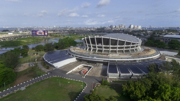 Aerial view of the Wole Soyinka Centre for Culture and Creative Arts National Theatre Nigeria with its unique circular roof and the city skyline in Lagos Lagos Nigeria. Aerial view of the Wole Soyinka Centre for Culture and Creative Arts National Theatre Nigeria with its unique circular roof and the city skyline in Lagos Lagos Nigeria.