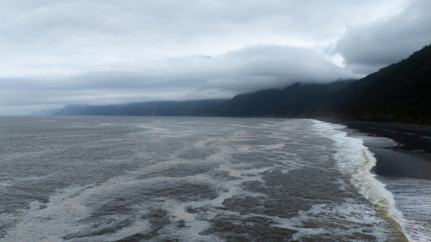 Aerial view of the rugged Lost Coast shoreline with crashing waves and fog covered forested mountains Humboldt County California United States.