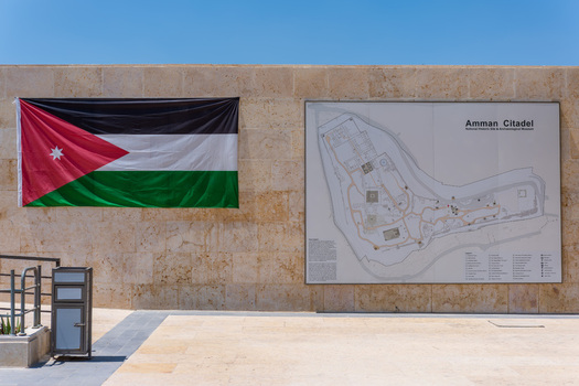 View of the Amman Citadel information board and the Jordanian flag displayed on a stone wall in Amman Amman Governorate Jordan.