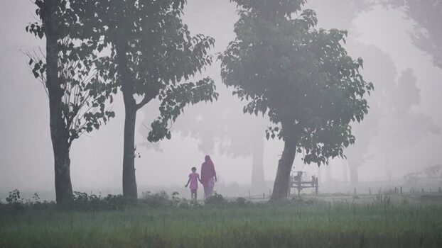 View of a woman and child walking in the fog Bangladesh.