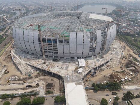 Aerial view of Jakarta International Stadium under construction with cranes and surrounding urban infrastructure in Tanjung Priok Jakarta Indonesia. Aerial view of Jakarta International Stadium under construction with cranes and surrounding urban infrastructure in Tanjung Priok Jakarta Indonesia.