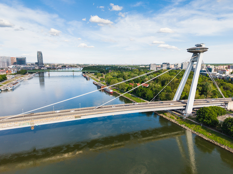 Aerial view of the Most SNP bridge with its iconic UFO observation deck spanning the Danube river under a blue sky in Bratislava Bratislava Region Slovakia. Aerial view of the Most SNP bridge with its iconic UFO observation deck spanning the Danube river under a blue sky in Bratislava Bratislava Region Slovakia.