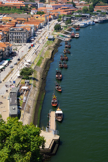 Aerial view of the Douro River reflecting the sky boats lining the shore near Ribeira district and buildings casting shadows in Porto Porto Portugal. Aerial view of the Douro River reflecting the sky boats lining the shore near Ribeira district and buildings casting shadows in Porto Porto Portugal.