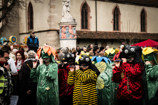 Basel Switzerland 10 March 2025 View of a vibrant Fasnacht parade where musicians in colorful insect costumes fill the square with music against the backdrop of a historic church and monument. Basel Switzerland 10 March 2025 View of a vibrant Fasnacht parade where musicians in colorful insect costumes fill the square with music against the backdrop of a historic church and monument.
