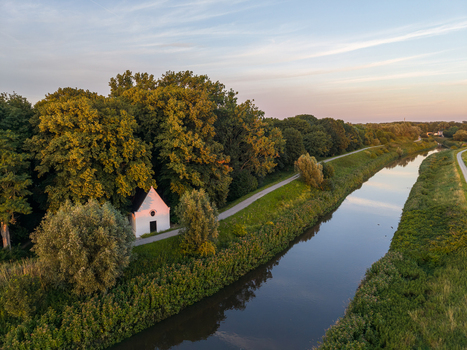 Aerial view of Kapel O L Vrouw in t Hammeke nestled among lush trees beside the Zenne river during a golden sunset in Zemst Flanders Belgium. Aerial view of Kapel O L Vrouw in t Hammeke nestled among lush trees beside the Zenne river during a golden sunset in Zemst Flanders Belgium.