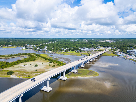 Aerial view of North Topsail Bridge spanning the waterway with surrounding marshlands coastal vegetation and scattered buildings in North Topsail Beach North Carolina United States.
