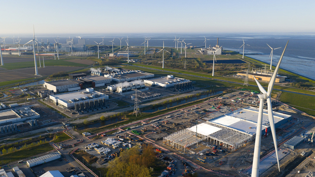 Aerial view of the industrial port area featuring numerous wind turbines large data centers and construction sites under a clear sky in Eemshaven Groningen Netherlands. Aerial view of the industrial port area featuring numerous wind turbines large data centers and construction sites under a clear sky in Eemshaven Groningen Netherlands.