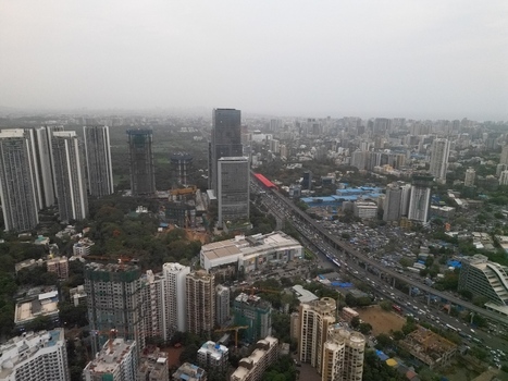 Aerial view of Malad East featuring high rise residential towers the busy Western Express Highway and dense urban development under a hazy sky in Mumbai Maharashtra India.