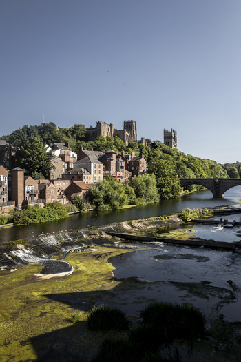 View of Durham Cathedral and Durham Castle overlooking the River Wear with historic buildings and a stone bridge in Durham England United Kingdom. View of Durham Cathedral and Durham Castle overlooking the River Wear with historic buildings and a stone bridge in Durham England United Kingdom.