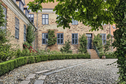 Viborg Denmark 07 August 2026 View of the historic courtyard of Viborg Stift with traditional brick architecture cobblestone ground and lush greenery in the Latinerhaven garden. Viborg Denmark 07 August 2026 View of the historic courtyard of Viborg Stift with traditional brick architecture cobblestone ground and lush greenery in the Latinerhaven garden.