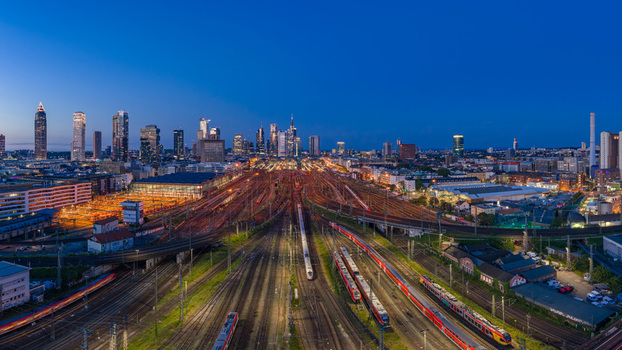 Aerial view of the Hauptbahnhof train station with illuminated tracks and the city skyline at twilight in Frankfurt am Main Hessen Germany.