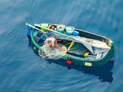 Aerial view of a small vibrant fishing boat bobs on the tranquil deep blue sea its nets and gear scattered about Ghajnsielem gozo Malta. Aerial view of a small vibrant fishing boat bobs on the tranquil deep blue sea its nets and gear scattered about Ghajnsielem gozo Malta.