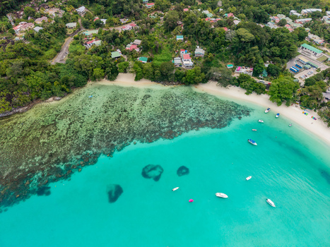 Aerial view of turquoise waters embrace the shoreline where lush greenery meets the soft sandy beach a tropical haven under the sun Victoria Mahe Island Seychelles. Aerial view of turquoise waters embrace the shoreline where lush greenery meets the soft sandy beach a tropical haven under the sun Victoria Mahe Island Seychelles.