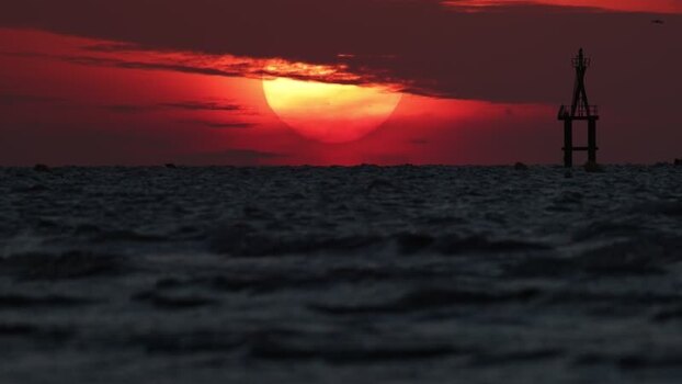 View of navigational beacon at sunset over sea France.