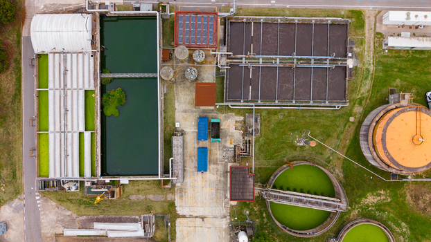Aerial view of the Depuratore di San Giuliano Milanese Ovest wastewater treatment plant with rectangular and circular tanks and green basins in Rancate Lombardia Italy.