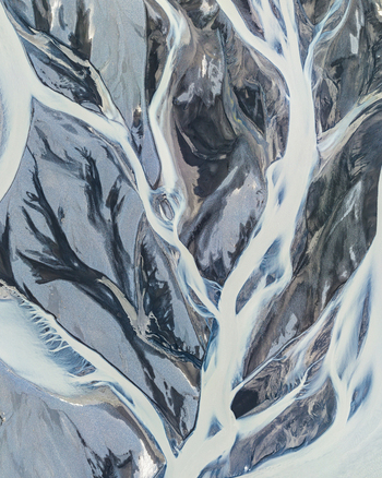 Aerial view of a complex braided river system with glacial meltwater flowing through dark volcanic sediment in Iceland. Aerial view of a complex braided river system with glacial meltwater flowing through dark volcanic sediment in Iceland.