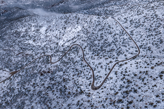 Aerial view of a winding serpentine road traversing the snow dusted slopes of the White Mountains in Mono County California United States.