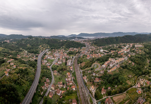 Aerial view of the town of Vezzano Ligure featuring the highway railway tracks surrounding green hills and residential buildings in Vezzano Ligure Liguria Italy.