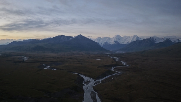 Aerial view of the Engilchek Glacier surrounded by winding rivers and rugged mountain peaks under a twilight sky in Ak Su Issyk Kul Region Kyrgyzstan. Aerial view of the Engilchek Glacier surrounded by winding rivers and rugged mountain peaks under a twilight sky in Ak Su Issyk Kul Region Kyrgyzstan.