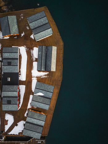 Aerial view of quaint buildings with snow dusted roofs meet the tranquil dark waters Henningsv&aelig;r Nordland Norway.
